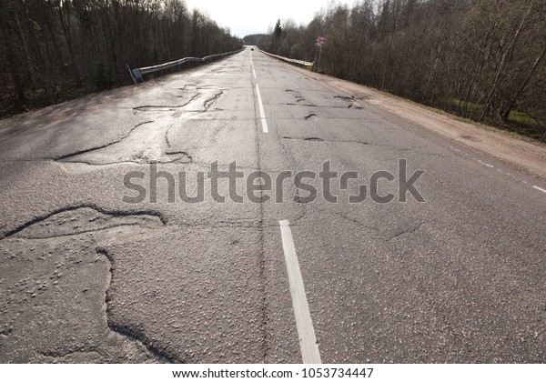 Bad\
quality road with potholes. Hole in asphalt. Pit, unsafe, hole\
road. Transportation, risk of movement by car\
