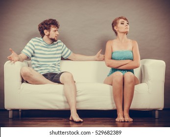 Bad Relationship Concept. Man And Woman In Disagreement. Young Couple Sitting On Couch At Home Having Quarrel, Offended Wife And Unhappy Husband