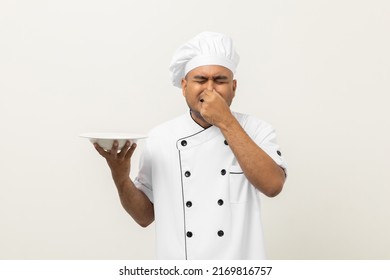 Bad Smell And Not Tasty Food. Young Asian Master Chef Holding Dish Has Rotten Food Dishes Smelly And Disgusting. Dirty Food With Chef On Isolated Background.