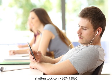 Bad Student Distracted Listening To Music Sitting In A Classroom