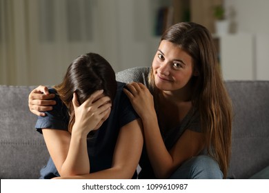 Bad Teen Is Happy With Her Sad Friend Crying Sitting On A Couch In The Living Room At Home