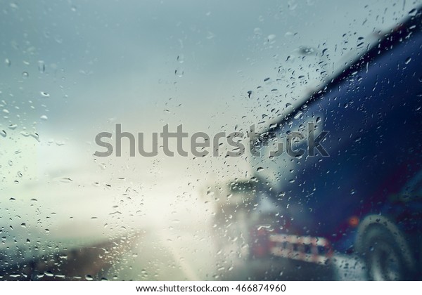 Bad weather conditions on the road during rain\
storm ,view through the wind shield of rainy day.Selective focus\
and color toned.