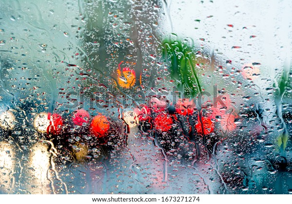 Bad weather, rain, street traffic photographed\
through wet glass.