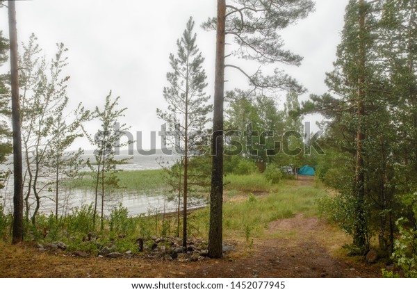 Bad weather for a recreation. Damp and\
rainy over the lake. On the shore among the bushes and trees there\
is a car and a tent, people hid from the\
damp.