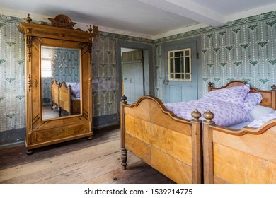 Bad Windsheim, Germany - 16 October 2019: Interior views of a german village house. View into the rural bedroom with colorful wallpaper and antique bed with farmhouse cupboard