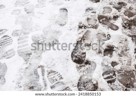 Bad winter pavement condition. Muddy footpath. Shoes imprints. Wet snow melting. Sidewalk covered with wet snow. Danger of slippery. Footprints texture. Slush on ground.