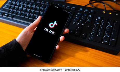 BADAJOZ, SPAIN - Apr 09, 2021: Spain, 04, 08, 2021  Hand Holding Phone With The TikTok Logo In Front Of A Black Background  Tiktokers Have Millions Of Fans 