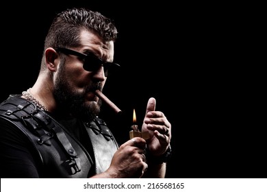 Badass biker lighting up a cigarette on black background