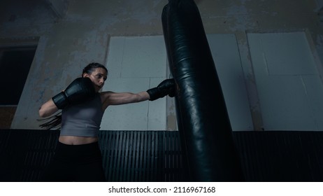 Badass Female Boxer Training Hard In An Old Boxing Gym Studio With Hair Braided And Wearing Boxing Gloves. Isolated Woman Athlete Warming Up Before Starting Sparring Sessions With Her Coach.