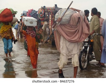 BADIN, PAKISTAN - SEPTEMBER 13: Rain affected people hold their households pass through a flooded area as they are moving towards safe place after heavy downpour of Monsoon season in Badin September 13,2011