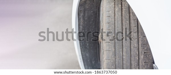 Badly worn out car tire tread and damaged bulb\
like side due to wear and tear or because of poor tracking or\
alignment of the wheels, dangerous for driving unsafe not safe for\
use copy space.