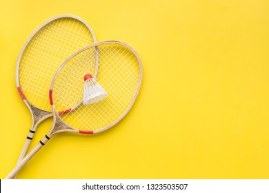 Badminton concept. Badminton rackets and shuttlecock on yellow background top view space for text