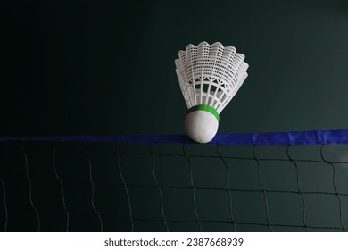Badminton net and shuttlecock in a green background. Close up in the shuttlecock