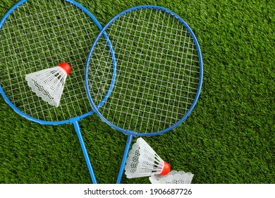 Badminton rackets and shuttlecocks on green grass outdoors, flat lay. Space for text