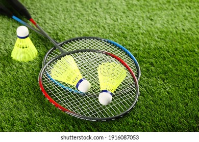 Badminton rackets and shuttlecocks on green grass outdoors, space for text