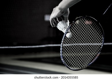 Badminton serving by player in indoor badminton court, soft and selective focus on string and shuttlecock.