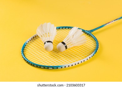 Badminton shuttlecock and badminton racket on yellow background