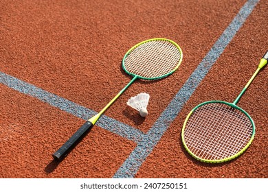 Badminton shuttlecocks and racket, placed in the corner of a synthetic field.