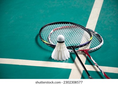 Badminton sport equipments, rackets and shuttlecocks on dark floor of indoor badminton court, soft focus, concept for badminton playing lovers around the world, copy space.