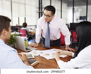 bad-tempered asian businessman yelling at two subordinates in office.