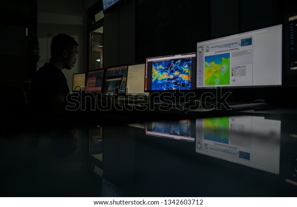 BADUNG/BALI-DECEMBER 07 2017: Observer or\
weather man observing the weather radar to make sure when and where\
the rain happens with multiple computer on the\
desk