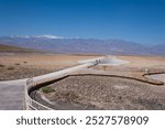 Badwater basin, Death Valley, USA. People walking out towards the lowest point. Sign post of Badwater basin in the foreground.