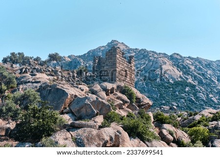 Bafa, Turkey - July 15, 2023: Bastion tower remains of ancient city of Latmos Herakleia with Geological gneiss rock formations