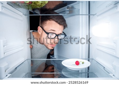 Baffled Man Looking Inside an Almost Empty Fridge