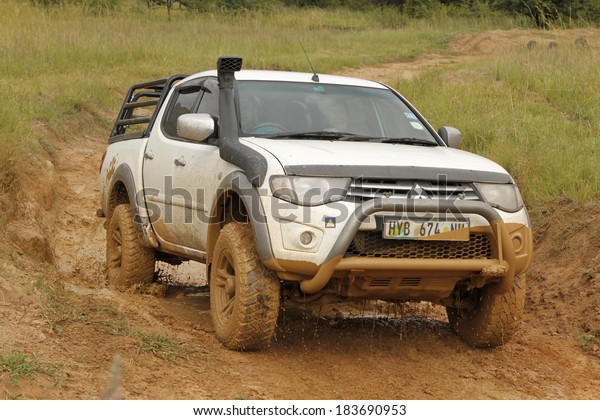 BAFOKENG - MARCH 8: White Toyota Triton DHD\
crossing mud obstacle at Leroleng 4x4 track on March 8, 2014 in\
Bafokeng, Rustenburg, South\
Africa
