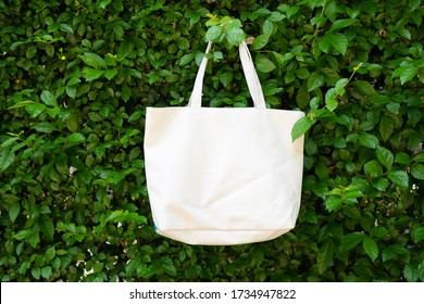 Bag canvas fabric for mockup blank template hanging at the background is a tree wall. - Powered by Shutterstock