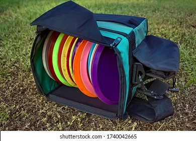 Bag of disc golf discs laying on grass.