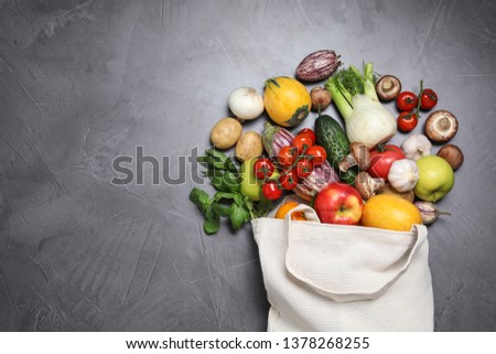 Bag with fresh vegetables and apples on dark background, flat lay. Space for text