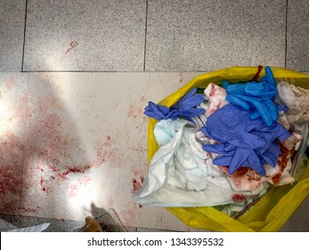 A Bag Full Of Clinical Waste And A Urine Bag On A Floor Covered With Dried Blood After A Major Operation In Which Heavy Bleeding Occurred.