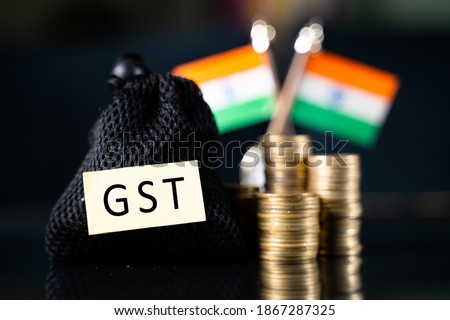 Bag with GST sticker in front of the stack of Coins and Indian flag as background - Concept goods and service indirect tax collection in India.