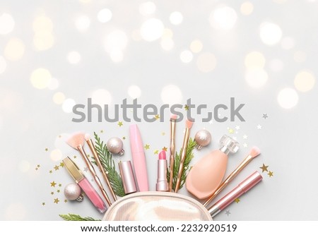 Bag with makeup cosmetics and Christmas decorations on light background with space for text