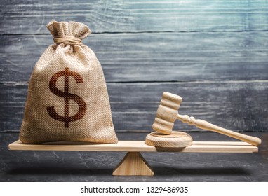 Bag of money with a dollar sign and a judge's hammer on the scales. Concept lobbying for the adoption of a law or a norms, corruption. Payment of fines and penalties. award of compensation for damage