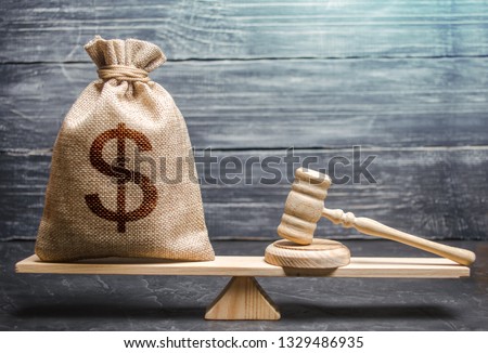 Bag of money with a dollar sign and a judge's hammer on the scales. Concept lobbying for the adoption of a law or a norms, corruption. Payment of fines and penalties. award of compensation for damage