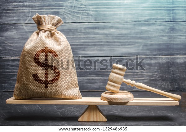 Bag of money with a dollar sign and a judge\'s\
hammer on the scales. Concept lobbying for the adoption of a law or\
a norms, corruption. Payment of fines and penalties. award of\
compensation for damage