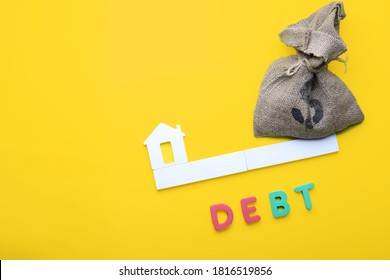 Bag With Money, Model Of House And Word DEBT On Color Background