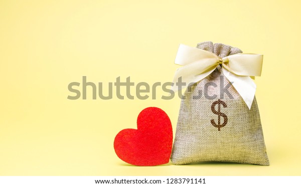 Bag with money and red heart. Valentine\'s Day.\
Saving money. Accumulation. Buying gifts to your loved one.\
Preparation for the\
holiday.