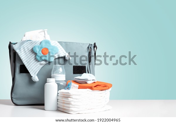 Bag\
packed for trip or journey or for walking with baby. Diapers,\
bottle and other necessary things for baby and mom. Diaper bag to\
maternity hospital. Copy space. Blue background.\
