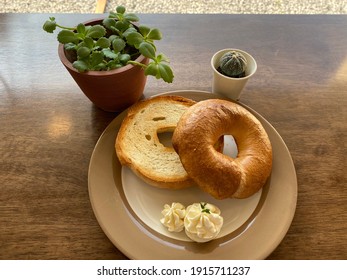 Bagel bread served with cream cheese on brown plate on wooden table