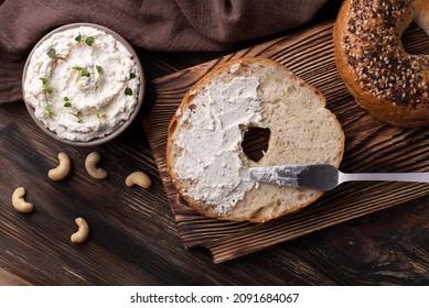 Bagel With Cashew Cream Cheese And Nuts On Dark Wooden Background, Fermented Vegan Nut Cheese.