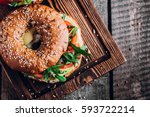 Bagels with cream, avocado, tomatos and arugula on wooden board and table background. Healthy breakfast food. Top view and Copy space