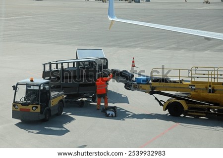 baggage handler wearing high visibility reflective suit unloading bags at the international airport