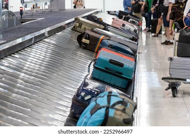 Baggage luggage at airport arrival carousel with passengers awiating to claim theirs - Shutterstock ID 2252966497
