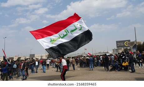 BAGHDAD, IRAQ - 1 March 2020 - A Man Is Waving The Flag Of Iraq Written In The Middle Of It 