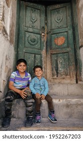 Baghdad, Iraq - April 8, 2017:  Two Kids Sitting On The Old Wood Door