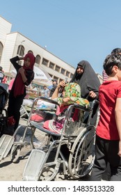 Baghdad, Iraq – July 5, 2019: At Baghdad Market One Woman Pushes Disabled Little Girl