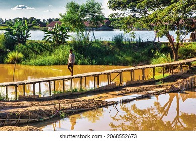 Bago, Myanmar - December 02 2012 : a Myanmar rural farmer person is walking over a bamboo bridge over a small river